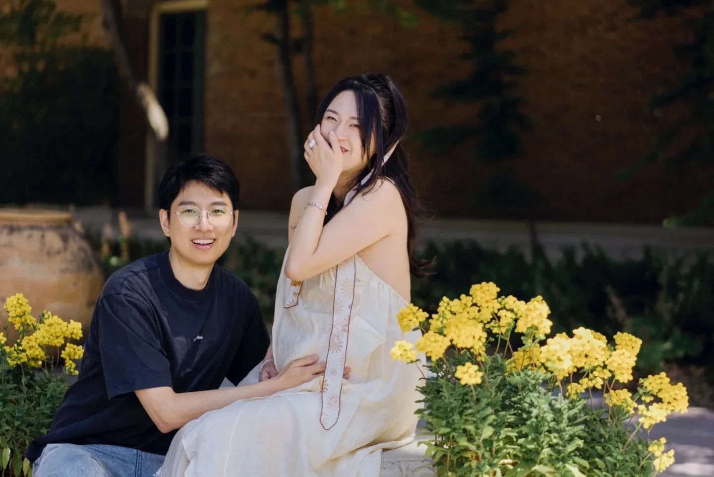 Parents and two young sons sitting together in a grassy field near the water.