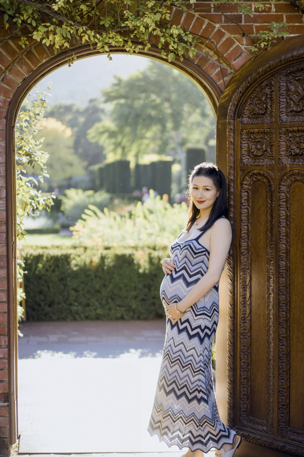 Expecting couple holding the baby bump in a grassy field during an outdoor maternity session.