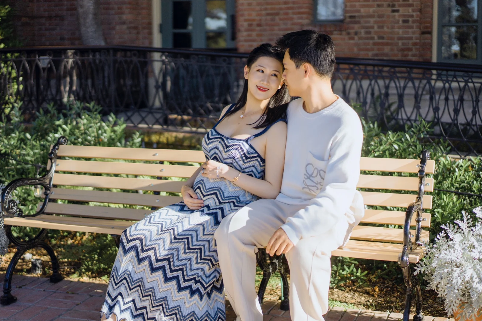 Expecting couple standing together on a rocky beach with their hands resting on the baby bump.