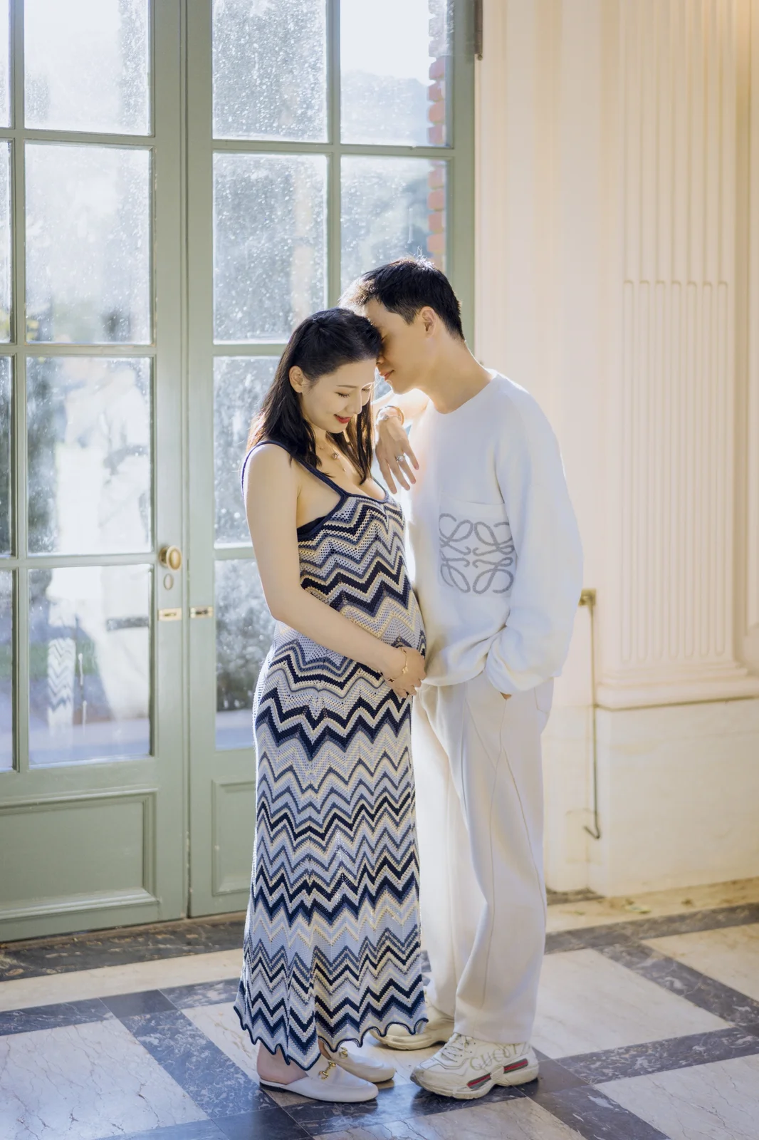 Partner kissing a pregnant woman's forehead during an intimate studio maternity session.
